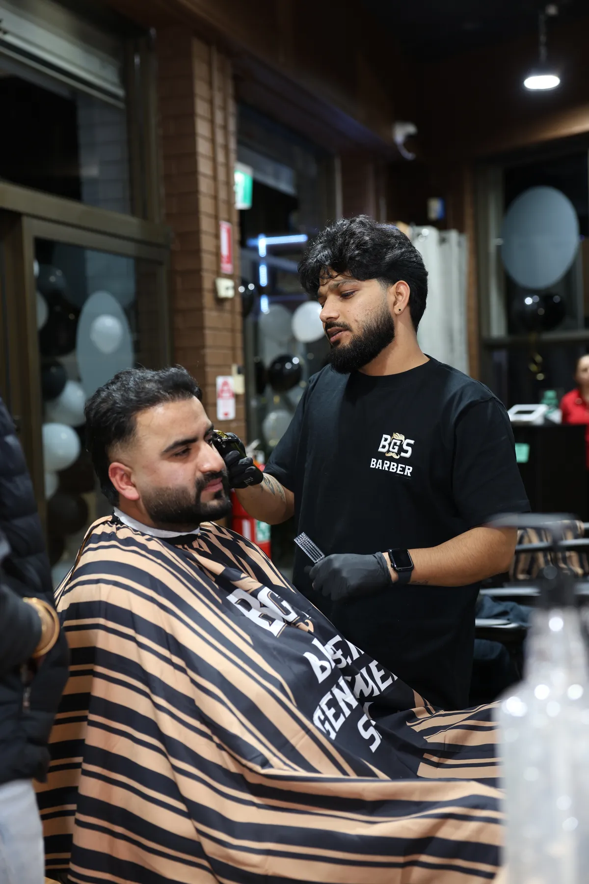 A BGS barber detailing a client's beard line with a trimmer