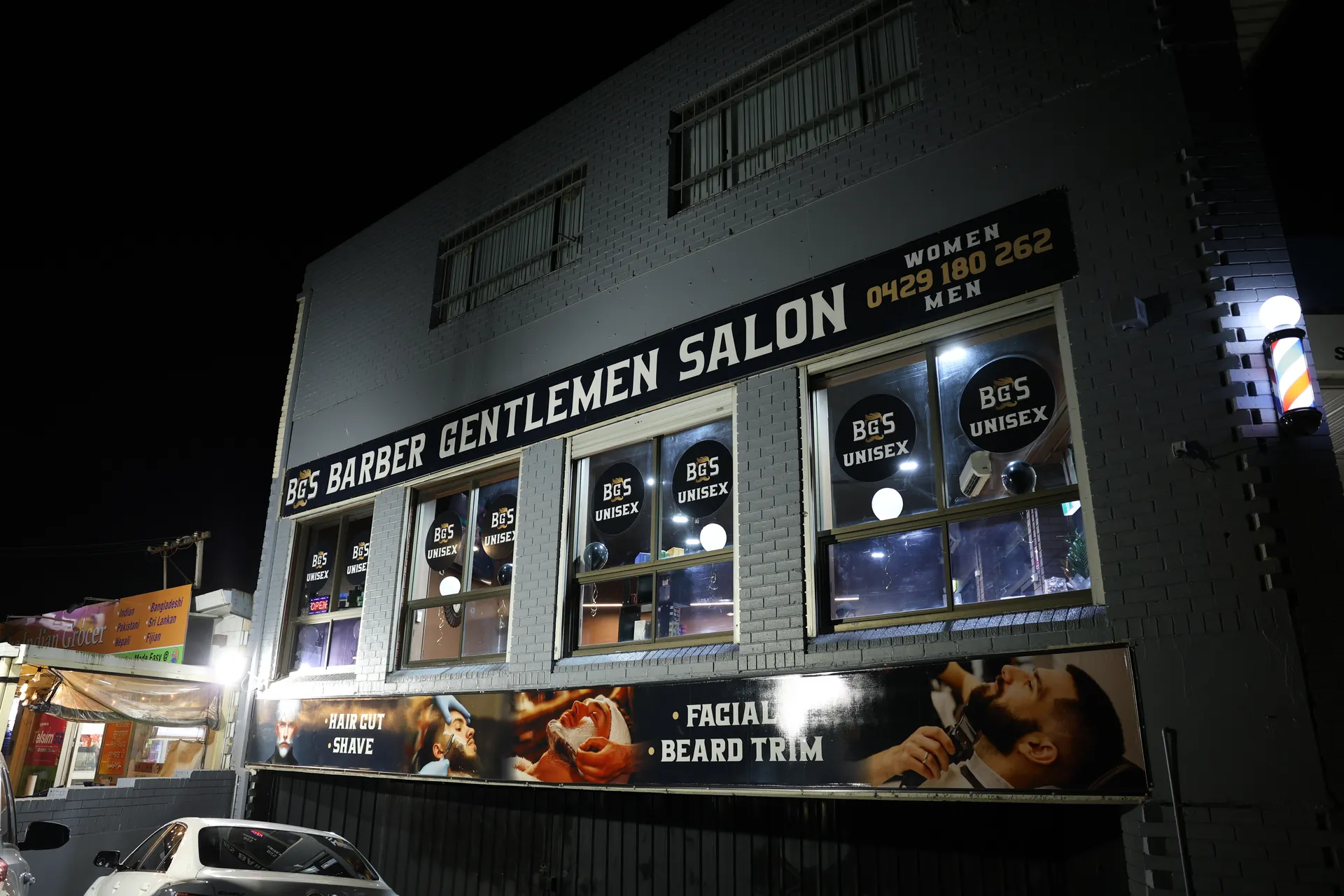 The Barber Gentlemen Salon shopfront lit at night, windows glowing
