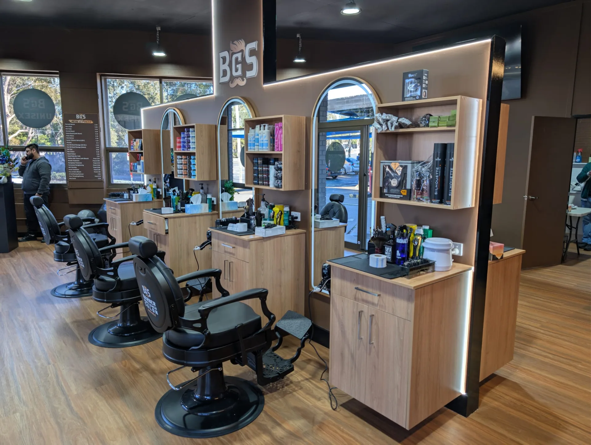 The row of barber chairs along the stations, services menu in the window